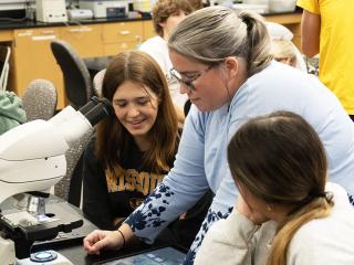 An image of Dr. Pamela Brown and two students looking at images from a microscope on a tablet. 