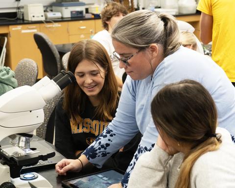 An image of Dr. Pamela Brown and two students looking at images from a microscope on a tablet. 